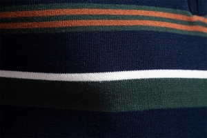Detail of multi-color striped knit fabric in navy, green, orange, and white texture