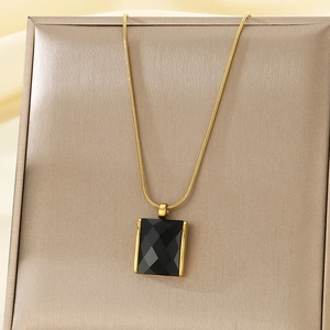 Detailed view of a gold snake chain necklace featuring a faceted black rectangular pendant