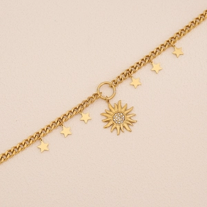 Gros plan sur une chaîne cubaine dorée ornée de pendentifs étoiles et soleil brillants