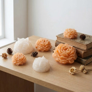 Detailed view of 3D peony silicone molds with finished handmade flower candles on wood