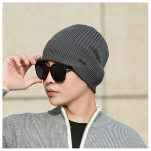 Detailed view of the dark gray ribbed knit beanie with a metallic side logo emblem