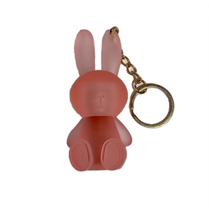 Pink matte translucent rabbit keychain with gold metal chain on a white background