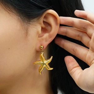 Detailed close-up of a golden starfish dangle earring with a polished metallic finish