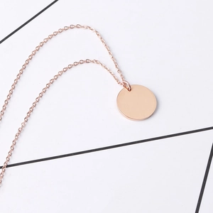 Detailed view of the rose gold round disc pendant on a delicate O-chain link necklace