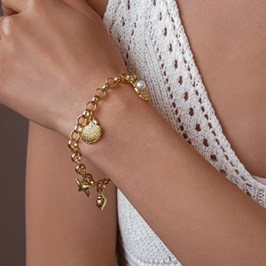 Gros plan d'un bracelet doré avec pendentifs coquillage et étoile de mer