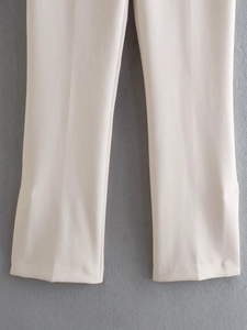 Detail view of beige straight-leg trousers with slit hem and smooth drape fabric
