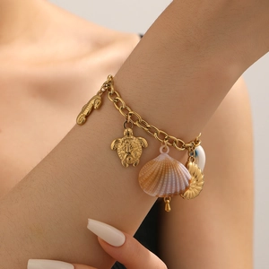 Close-up of golden beach-style bracelet with sea shell, turtle and seahorse charms