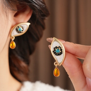 Close-up of vintage eye-shaped earrings with blue heart stone and amber water droplets