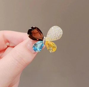 Detailed view of a butterfly brooch featuring four multi-colored pear-shaped gemstones