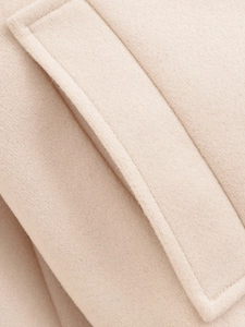 Detailed close-up of beige wool jacket pocket with high-quality stitching and fabric texture