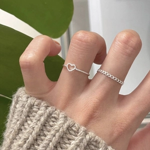Close-up of dual S925 silver heart rings set worn on hand with cozy knit background