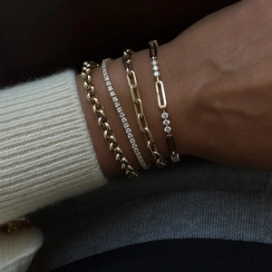 Set of four gold-plated tennis bracelets with zircons worn on a cozy knitted sleeve