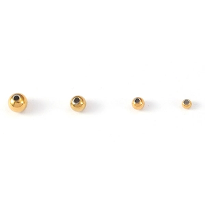 Detail of four golden stainless steel beads in various sizes for DIY jewelry making