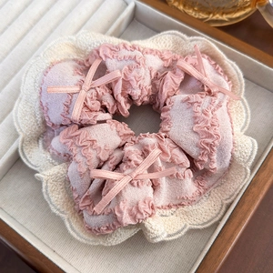 Detail of pink fabric scrunchie with beige lace edges and decorative mini bows
