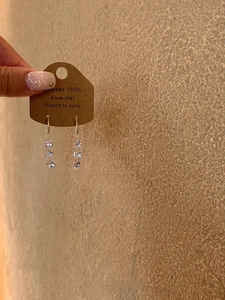 Detailed view of copper drop earrings featuring three vertically set zircon crystals