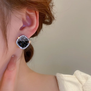 Close-up of geometric square earrings with sparkling crystals and silver needle studs