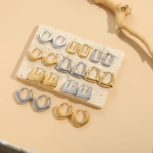 Selection of geometric gold and silver earrings displayed on minimalist stone pedestals