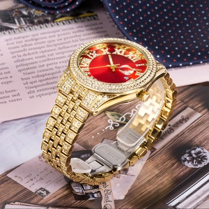 Detail shot of golden diamond-encrusted watch with red dial and stainless steel clasp