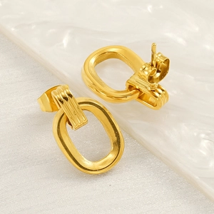 Boucles d'oreilles ovales dorées minimalistes avec texture verticale sur plat en céramique