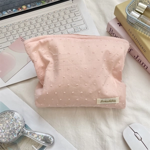 Detailed view of pink floral makeup bag with textured dot fabric and brand label
