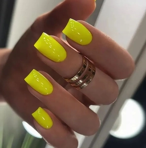 Macro detail of glossy fluorescent yellow square press-on nails with golden ring accessory
