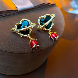 Vintage heart earrings with green stones and red rose drops on a velvet jewelry box