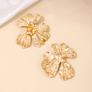 Exaggerated gold flower stud earrings with central pearls on silk background
