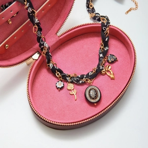 Détail du collier rétro avec pendentifs cœur noir et fleurs sur velours rose