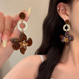 Macro view showing large amber texture flower earrings with yellow crystal core and gold rings