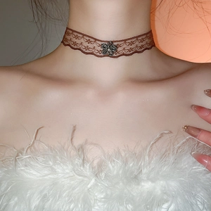 Detail of brown lace choker necklace with dark metal flower and crystal centerpiece