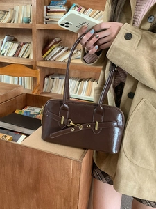 Brown PU leather bowling bag with gold hardware held in a bookstore setting