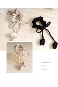 Detail of elegant black and beige satin hair scrunchies with tulip pendant ribbons