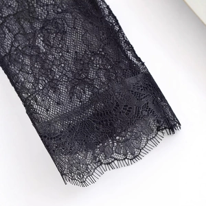 Close-up of elegant black lace dress featuring intricate floral patterns and eyelash trim