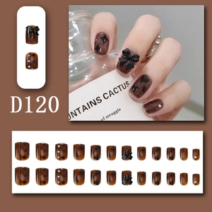 Close-up of D120 press-on nails with brown glossy finish, black hearts and 3D bows