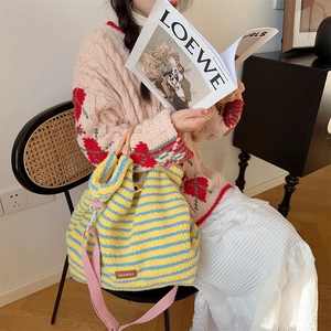 Close-up of blue and yellow striped plush bucket bag with pink strap and drawstring