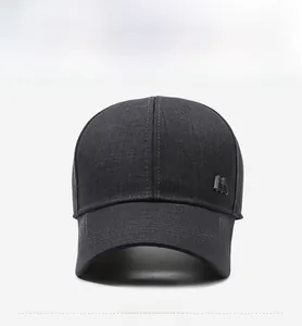 Detail of grey twill baseball cap with silver metal M logo and reinforced brim stitching