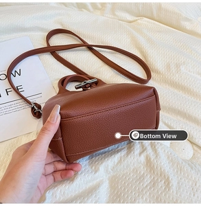 Detail view of the rectangular base and stitching of a brick red mini bamboo handle bag