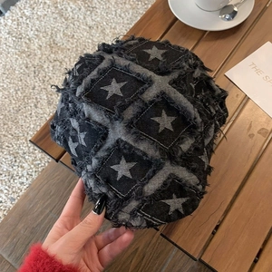 Close-up of retro grey patchwork beret with star embroidery on a wooden table setup