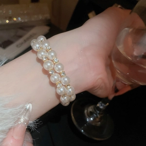 Elegant double-layer pearl bracelet with rhinestones worn by a model in a social setting