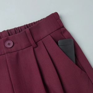 Detail view of burgundy suit pants featuring elastic back waist and deep side pockets