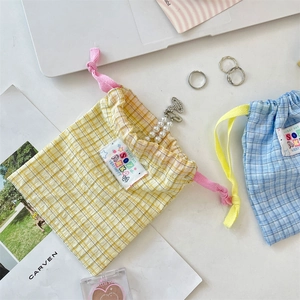 Detail of yellow and blue plaid drawstring bags with SOZ AKA tags and pearl charm