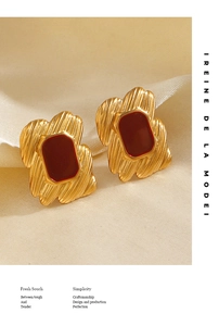 Detail of vintage square 18K gold-plated earrings with deep red enamel inlay on fabric