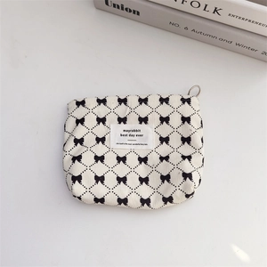 Close-up of canvas makeup bag featuring bow pattern, lattice print and metal ring zipper