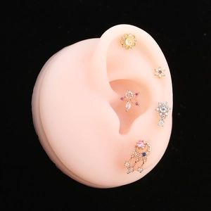 Détail de cinq clous d'oreilles en cristal sur un modèle d'oreille avec étoile et lune
