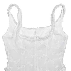 Detail of white backless dress featuring floral jacquard texture and ruffle trim detailing