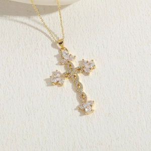 Elegant gold cross necklace with pear-cut cubic zirconia on a textured stone base