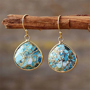 Close-up of bohemian teardrop earrings with turquoise stones and gold foil accents