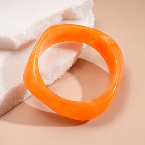 Detail view of bold orange resin chunky bangle with unique marble texture patterns