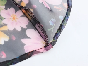Detail view of pink floral pattern on black organza fabric with neat edge stitching