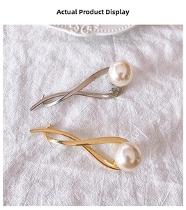 Detail of twisted alloy hair clips in gold and silver finish with large pearl accent